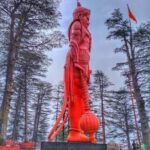 108 feet tall orange Lord Hanuman statue at Jakhoo Temple Shimla surrounded by pine trees